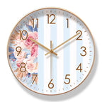 Round wall clock with floral design and gold casing on a white background

