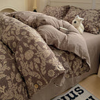 Bed with floral-patterned bedding and a plush toy on a wooden floor.

