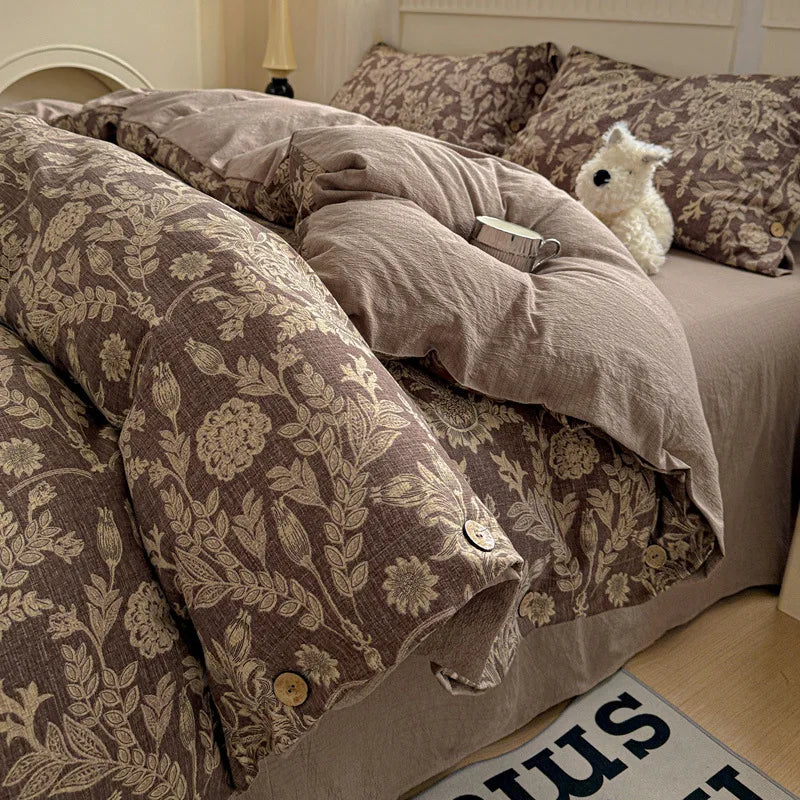 Bed with floral-patterned bedding and a plush toy on a wooden floor.

