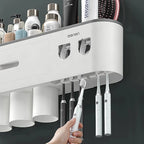 White electric toothbrush charging station with multiple toothbrushes and a hand holding a toothbrush.

