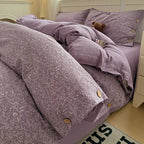 Purple floral-patterned comforter set on a bed with matching pillows.

