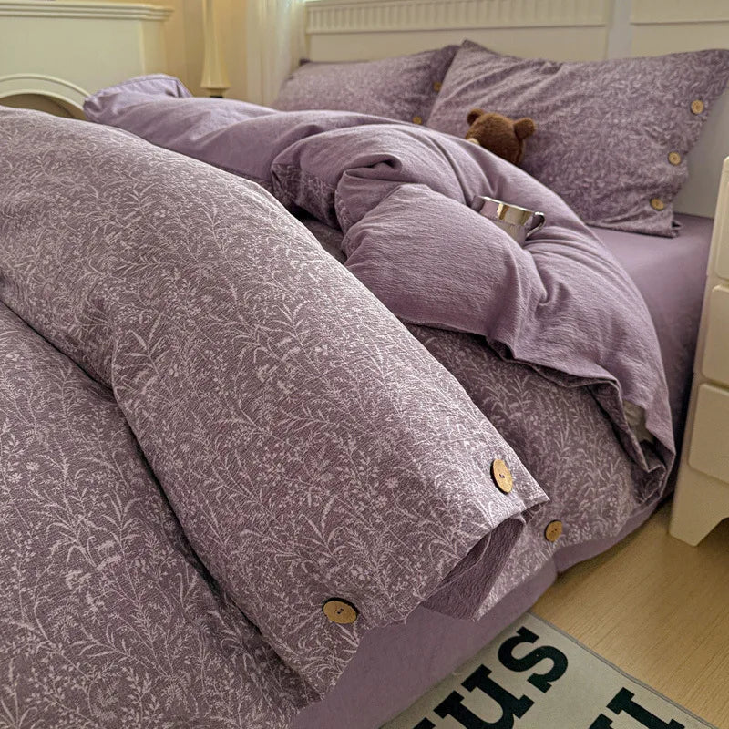 Purple floral-patterned comforter set on a bed with matching pillows.

