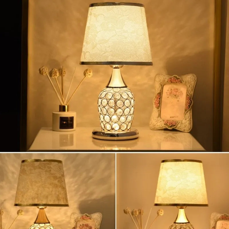 Decorative table lamp with textured base and white shade on a surface, surrounded by a diffuser and decorative pillow.

