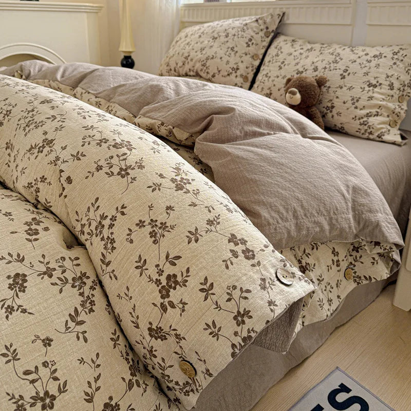 Floral patterned bedding set on a bed with a teddy bear and pillows.

