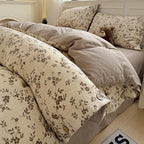 Floral patterned bedding set on a bed with a teddy bear and pillows.

