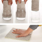 Gray microfiber cloth being used to clean a glass and a surface.

