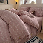 Pink floral bedspread on a bed with a teddy bear, in a softly lit bedroom.

