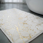 White bath mat with gold marble pattern on a bathroom floor.

