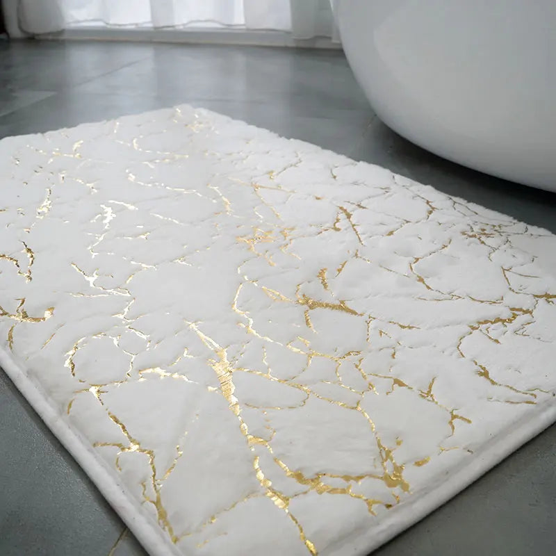 White bath mat with gold marble pattern on a bathroom floor.

