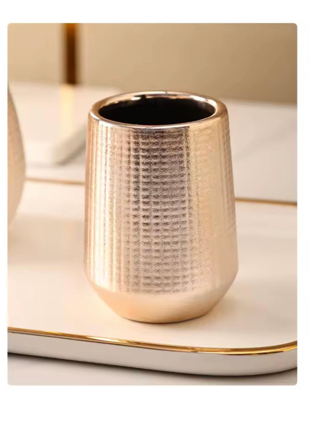 A textured metallic gold cup with a hammered pattern, sitting on a white tray with gold trim.

