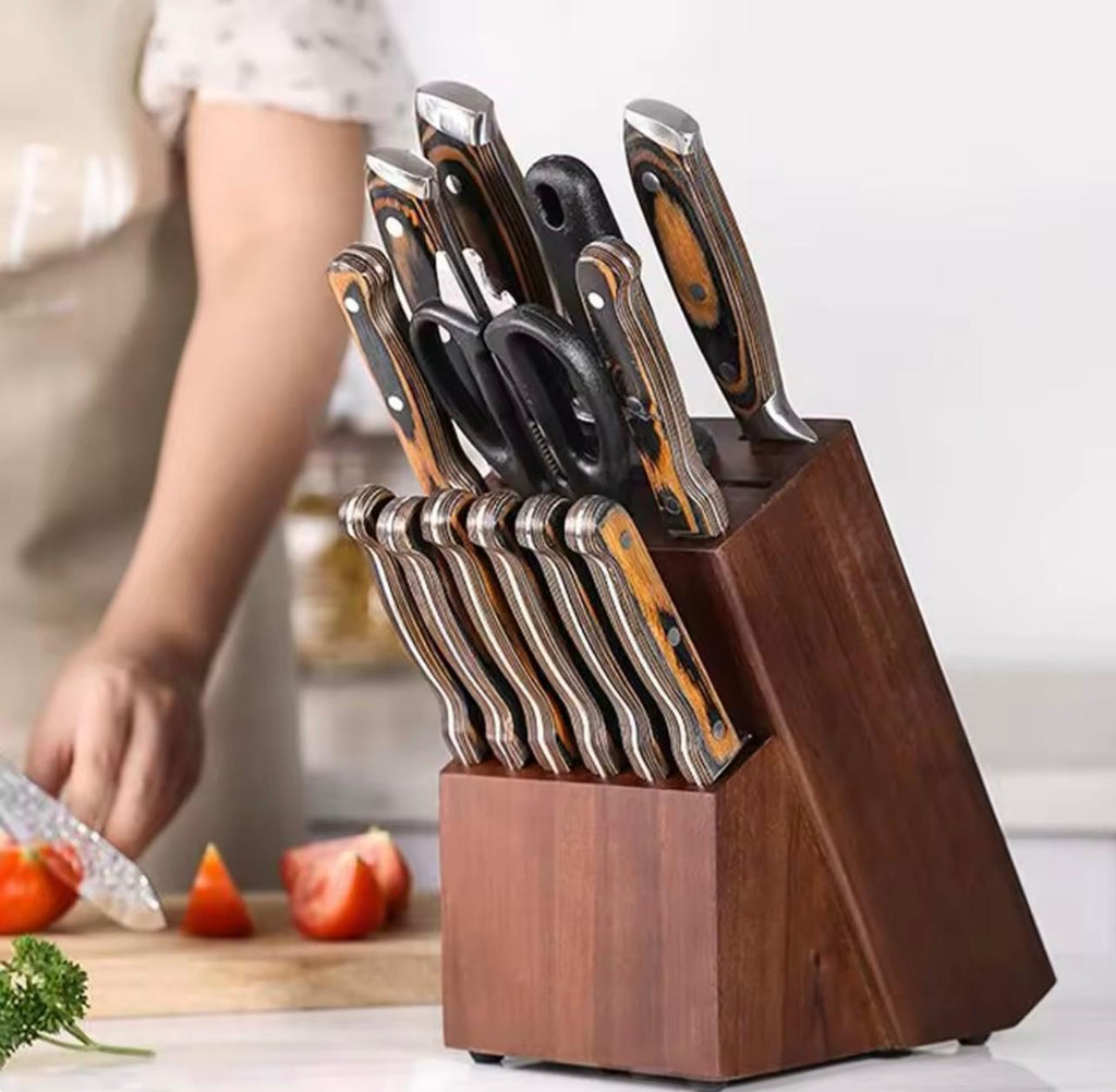 A dark wood knife block filled with kitchen knives and scissors, shown in a kitchen setting with a person cutting tomatoes in the background.

