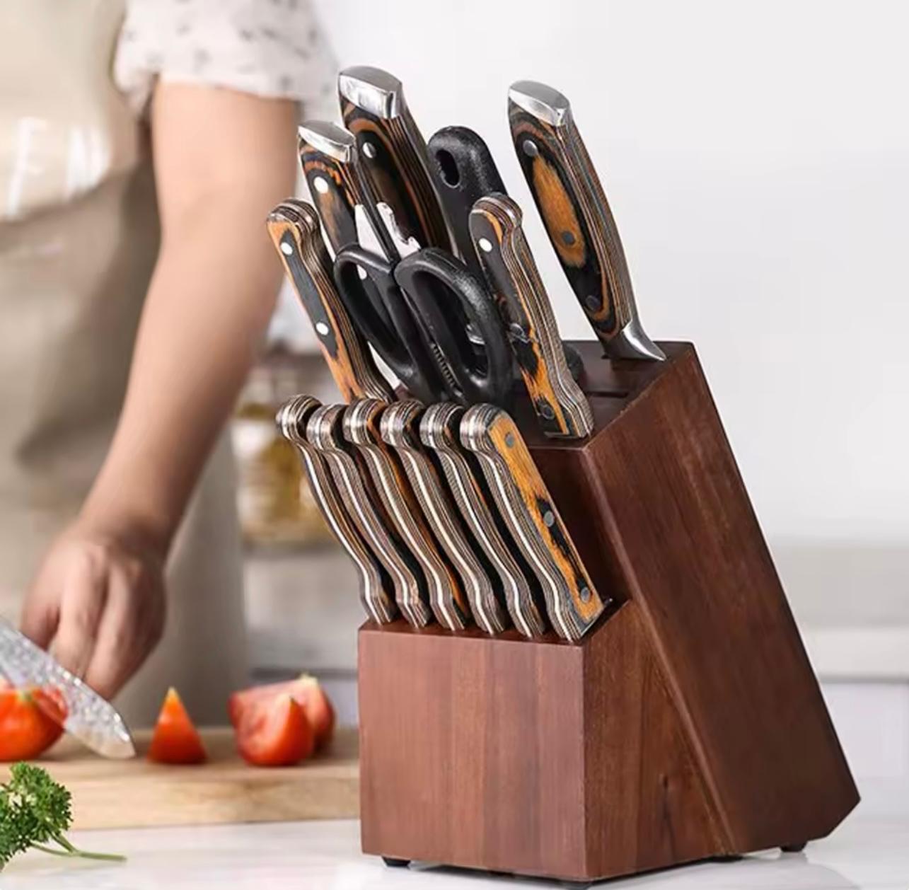 A dark wood knife block filled with kitchen knives and scissors, shown in a kitchen setting with a person cutting tomatoes in the background.

