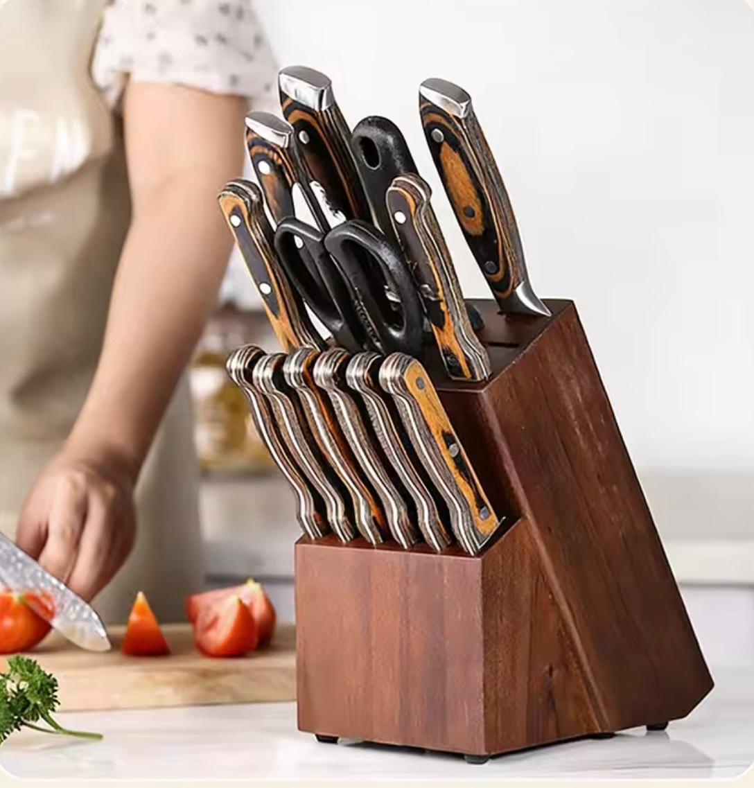 A wooden block knife block holding a set of kitchen knives and scissors, shown on a countertop with a person slicing tomatoes in a blurred background.

