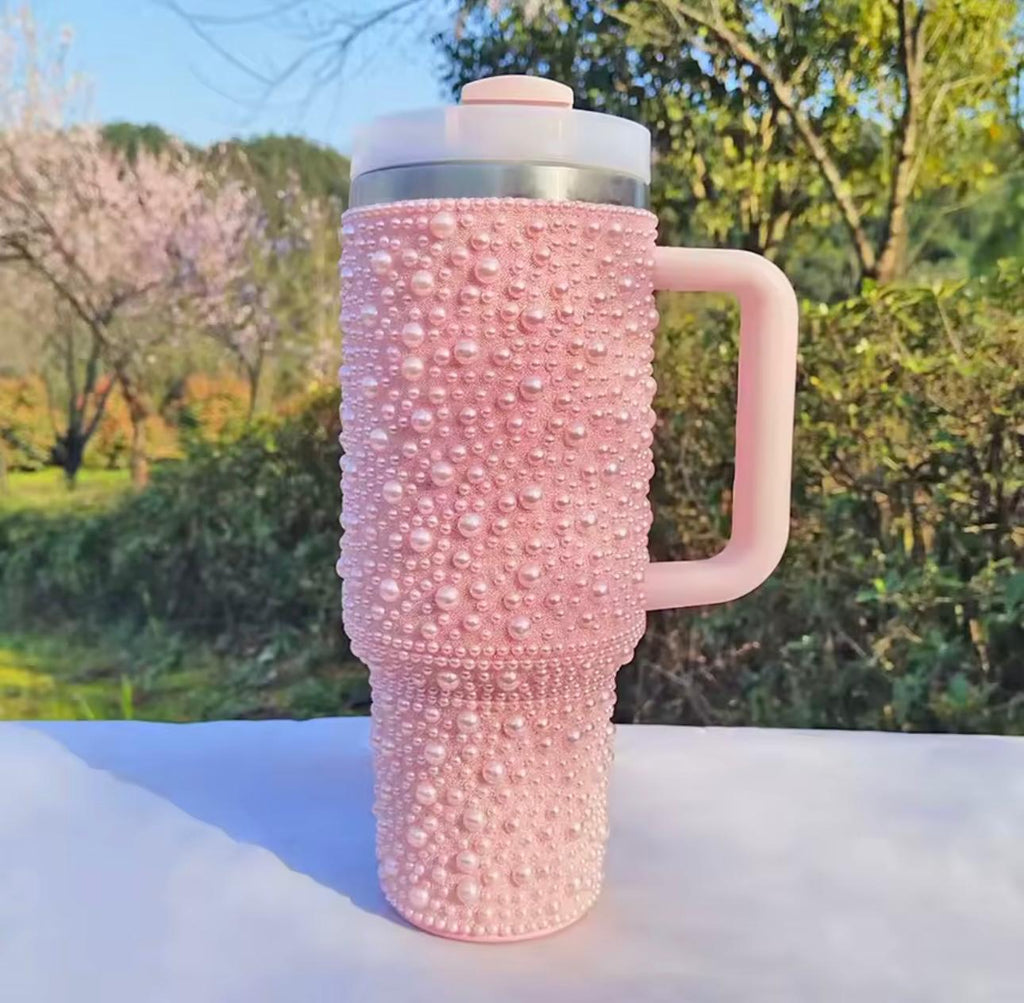 A pink travel tumbler with a textured, pearl