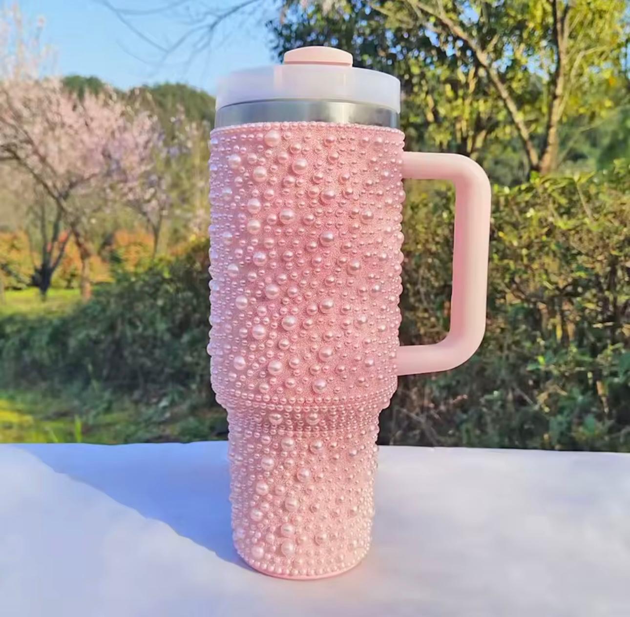 A pink travel tumbler with a textured, pearl