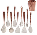 An 8-piece silicone kitchen utensil set with dark brown wood-grain handles and rose gold metal collars, shown alongside a matching wooden cutting board on a white background.

