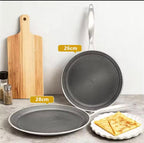 A set of non-stick cookware shown on a countertop against a light wall: a rectangular wooden cutting board, a frying pan labeled 26cm, a shallow round pan labeled 28cm, and a small plate with folded pancakes. Yellow size callouts indicate the pan diameters.

