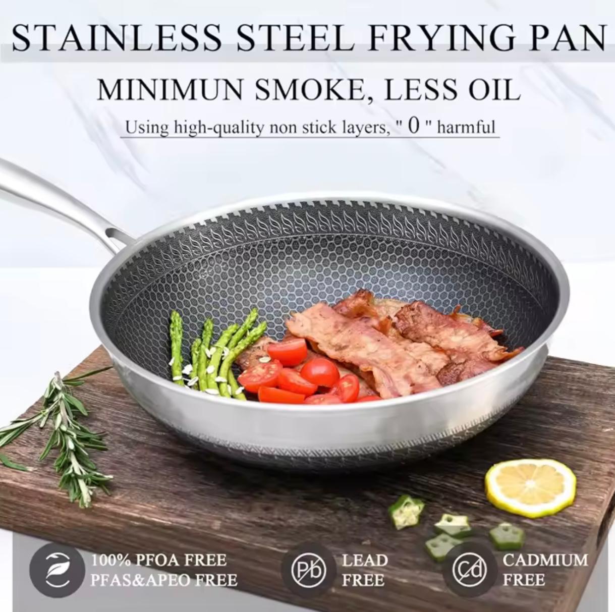 Stainless steel frying pan with a textured honeycomb interior, shown cooking bacon, asparagus, and tomatoes on a wooden cutting board. The image includes marketing text at the top and feature icons at the bottom.

