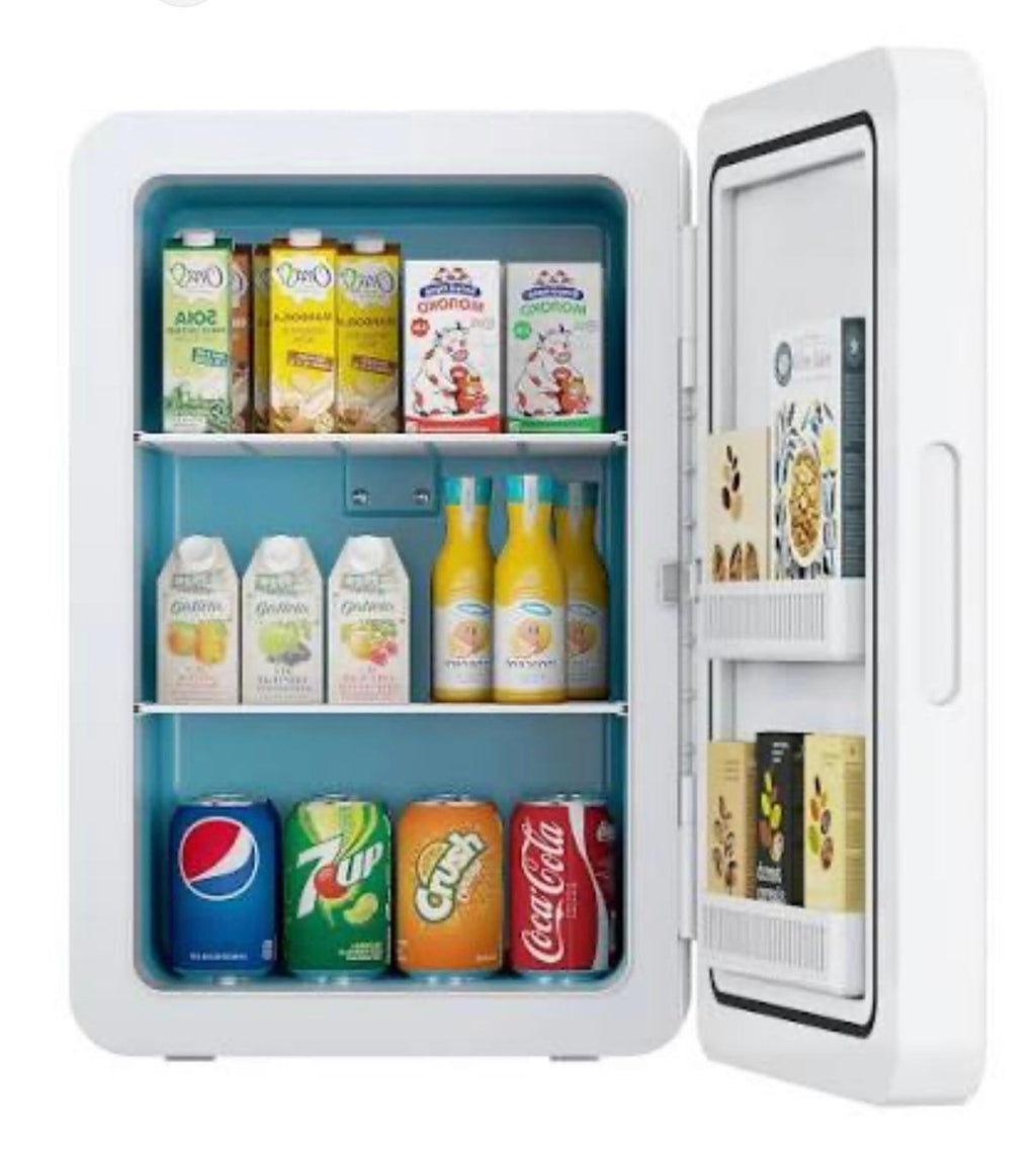 A white mini refrigerator shown open, filled with assorted beverages including juice bottles, milk cartons, and canned sodas, on a plain white background.

