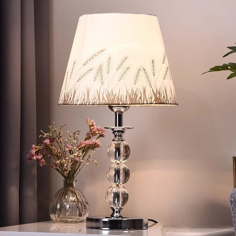 Decorative table lamp with a floral-patterned shade on a surface with a blurred background

